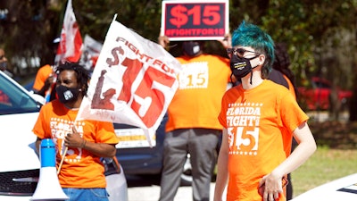 Cristian Cardona, right, an employee at a McDonald's, attends a rally for a $15 an hour minimum wage on Feb. 16 in Orlando, FL.