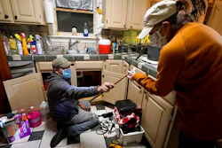 In this Feb. 20 photo, Handyman Roberto Valerio, left, hands homeowner Nora Espinoza the broken pipe after removing it from beneath her kitchen sink in Dallas. The pipe broke during freezing temperatures brought by last week's winter weather.