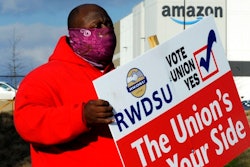 Michael Foster of the Retail, Wholesale and Department Store Union holds a sign outside an Amazon facility where labor is trying to organize workers on Tuesday, Feb. 9, 2021. For Amazon, a successful effort could motivate other workers to organize. But a contract could take years, and Amazon has a history of crushing labor organizing.