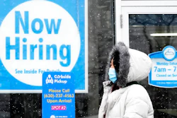 In this Feb. 6, 2021 file photo, a woman walks past a 'Now Hiring' sign displayed at a CD One Price Cleaners in Schaumburg, Ill. In a stark sign of the economic inequality that has marked the pandemic recession and recovery, Americans as a whole are now earning the same amount of wages and salaries that they did before the pandemic struck, even with nearly 9 million fewer people at work.