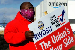 In this Feb. 9 file photo, Michael Foster of the Retail, Wholesale and Department Store Union holds a sign outside an Amazon facility where labor is trying to organize workers in Bessemer, Ala.