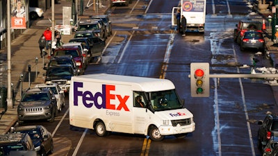 In this Dec. 29, 2020 photo, a FedEx delivery vehicle makes a U-turn near the Denver Pavilions, in downtown Denver.