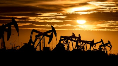 In this Feb. 2, 2020 photo, pump jacks operate in an oilfield as the sun begins to set on the horizon in Midland, Texas.