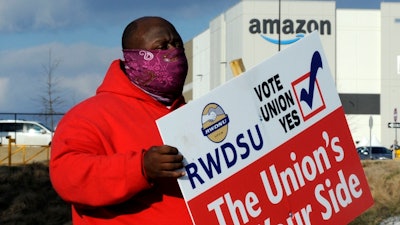In this file photo, Michael Foster of the Retail, Wholesale and Department Store Union holds a sign outside an Amazon facility in Bessemer, Alabama.