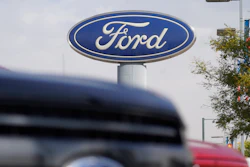 In this file photo, the Ford logo hangs over a row of 2020 F-150 pickup trucks at a dealership in Denver.