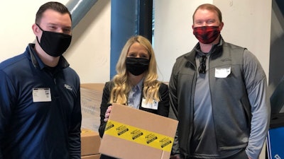 From Left: Kimball Midwest sales representative Joey Darke; director of culture, diversity and inclusion Meaghan McCurdy; and district manager Ben Darke hold a box containing donated Kimball Midwest supplies Thursday at Ford Field in Detroit. The donation supported COVID-19 mass vaccination sites at multiple NFL stadiums in partnership with the National Association of Wholesaler-Distributors.