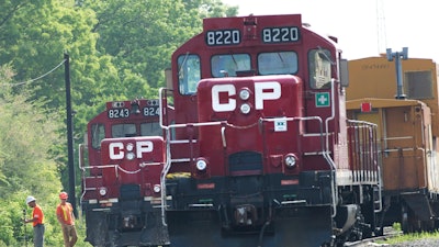 In this May 23, 2012, file photo, surveyors work next to Canadian Pacific Rail trains which are parked on the train tracks in Toronto.