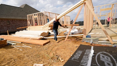 A workman carries beam at a new housing site in Madison County, Miss. on March 16.