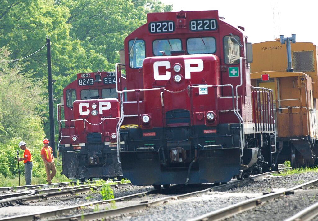 In this May 23, 2012 file photo, surveyors work next to Canadian Pacific Rail trains which are parked on the train tracks in Toronto.