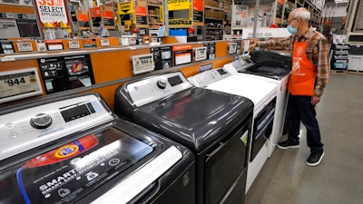 In this Oct. 29, 2020 photo, worker Javad Memarzadeh of Needham, MA dusts washers on a display at a Home Depot location in Boston.