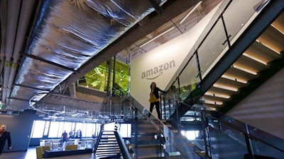 In this Sept. 27, 2017, file photo, an Amazon worker walks down steps in a company office before an event announcing several new Amazon products by the company in Seattle. Amazon plans to have its employees return to the office by fall as the tech giant transitions away from the remote work it implemented for many workers due to the coronavirus pandemic. On Tuesday, March 30, 2021, the company told employees it is planning a 'return to an office-centric culture as our baseline.'