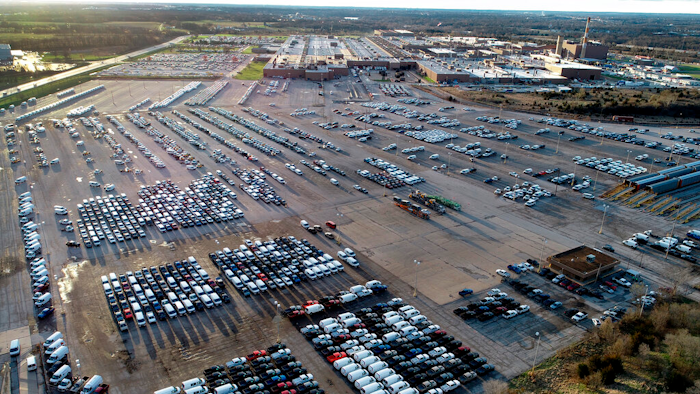 In this aerial photo, a General Motors assembly plant is seen at top right while mid-sized pickup trucks and full-size vans currently produced at the plant are seen in a parking lot outside on March 24 in Wentzville, Mo.