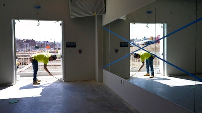 In this March 22 photo, a construction worker is reflected in a wall mirror at Polar Park, Worcester Red Sox's Triple-A baseball stadium, in Worcester, Mass., where preparations are ongoing for the club's opening day in May.