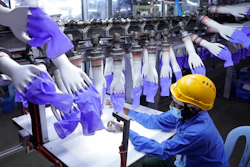In this Aug. 26, 2020 photo, a worker inspects disposable gloves at the Top Glove factory in Shah Alam on the outskirts of Kuala Lumpur, Malaysia.