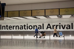 Passengers walk past a sign in the arrivals area at Heathrow Airport, London, Jan. 26, 2021.
