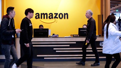 In this Feb. 14, 2019, file photo, people stand in the lobby for Amazon offices in New York. Amazon, which has been under pressure from shoppers, brands and lawmakers to crack down on counterfeits on its site, said Monday, May 10, 2021, that it blocked more than 10 billion suspected phony listings last year before any of their offerings could be sold.