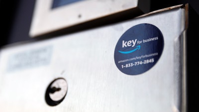 A blue sticker with the Amazon logo is displayed on a buzzer system in the apartment building of Jason Goldberg, chief commerce strategy officer at marketing company Publicis Communications, Monday, March 29, 2021, in Chicago. Amazon is making a push to install a device on buzzer systems in apartment buildings throughout the country that allows its delivery drivers to whip out a phone, tap a button and unlock a building's front doors whenever they need to leave packages in the lobby instead of the street.