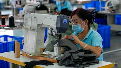 Workers wearing face masks to help curb the spread of the coronavirus sew layers for ice-skating shoes at a manufacturing factory in the ice and snow sports equipment industry park in Zhangjiakou in northwestern China's Hebei province on July 15.