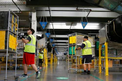 In this Dec. 17, 2019, file photo, Amazon workers move containers to delivery trucks at an Amazon warehouse facility in Goodyear, Ariz. Starting Monday, Aug. 9, 2021, Amazon will be requiring all of its 900,000 U.S. warehouse workers to wear masks indoors, regardless of their vaccination status. The move follows steps by a slew of other retailers, including Walmart and Target, to mandate masks for their workers. In many of those cases the mandates apply to workers in locations of substantial COVID-19 transmission.