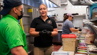 Sarah White, center, area manager of Lost Dog Cafe, trains manager Alex Aleman, left, in a new pasta preparation technique, as they work at the cafe in Fairfax, Va., on Aug. 27.