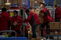 Employees of a private delivery company sort out parcels at a distribution center in Beijing, April 27, 2020.