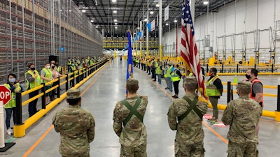 The North Dakota State University Color Guard leads associates through the Fargo Amazon Fulfillment Center's opening ceremony.