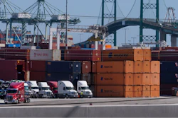 In this Tuesday, Oct. 19, 2021, photo trucks line up next to containers at the Port of Los Angeles in san Pedro, Calif.