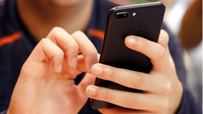 In this Sept. 16, 2017, file photo, a person uses a smart phone in Chicago. Most Americans across party lines have serious concerns about cyber attacks on U.S. computer systems and view China and Russia as major threats. That's according to a new poll by The Pearson Institute and the Associated Press-NORC Center for Public Affairs Research