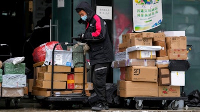 A worker of a private delivery company, wearing a face mask, sorts out parcels at its distribution center in Beijing on Nov. 7, 2021.