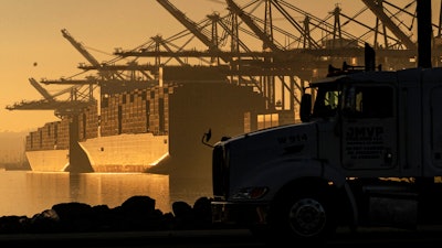 A truck arrives to pick up a shipping container near vessels moored at Maersk APM Terminals Pacific at the Port of Los Angeles on Nov. 30, 2021.
