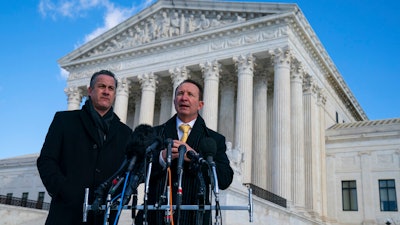 Louisiana Attorney General Jeff Landry talks to reporters outside the Supreme Court after arguments about whether to allow the administration to enforce a vaccine-or-testing requirement that applies to large employers and a separate vaccine mandate for most health care workers on Jan. 7, 2022, in Washington. At left is deputy Louisiana Attorney General Bill Stiles.