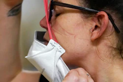 Registered nurse Jessalynn Dest pulls on a new N95 mask as indentations remain from another she had just removed after leaving a COVID-19 patient room in the acute care unit of Harborview Medical Center on Jan. 14, 2022, in Seattle.