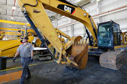 A Puckett Machinery Company technician walks past a new heavy duty Caterpillar excavator that awaits modification at Puckett Machinery Company in Flowood, Mississippi on Sept. 18, 2019.