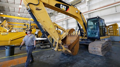 A Puckett Machinery Company technician walks past a new heavy duty Caterpillar excavator that awaits modification at Puckett Machinery Company in Flowood, Mississippi on Sept. 18, 2019.