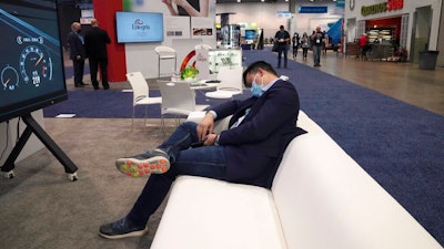 An attendee rests on a couch during the CES tech show Thursday, Jan. 6, 2022, in Las Vegas.