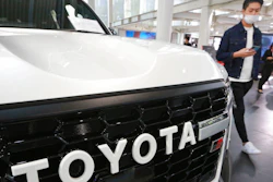 A man walks by the logo on a Toyota car at a showroom in Tokyo on Oct. 18, 2021. The shortage of parts caused by the coronavirus pandemic is further denting production at Toyota, Japan’s top automaker.