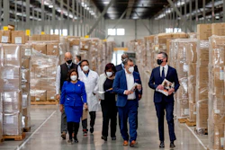 Gov. Gavin Newsom, right, walks through rows of boxed Personal protective equipment, PPE, with dignitaries and elected officials, as he prepares to announce the next phase of California's COVID-19 response called 'SMARTER,' during a press conference at the UPS Healthcare warehouse in Fontana, CA on Feb. 17, 2022.