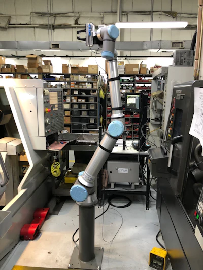 The UR10e robotic arm that feeds the CNC machines, one on either side of it.