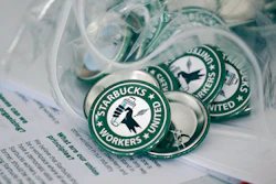 Pro-union pins on a table during a watch party for Starbucks' employees union election, Dec. 9, 2021, Buffalo, N.Y.