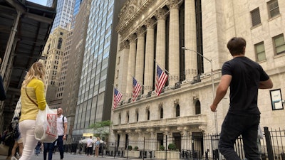 Pedestrians walk by the New York Stock Exchange, May 18, 2022.