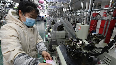 A worker operates a machine in a factory in Funan county, China, March 1, 2022.