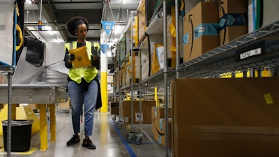 Tahsha Sydnor sorts packages at an Amazon warehouse, Goodyear, Ariz., Dec. 17, 2019.