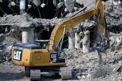 A Caterpillar machine works on the demolition of a building in downtown Pittsburgh, April 28, 2022.