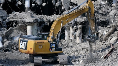 A Caterpillar machine works on the demolition of a building in downtown Pittsburgh, April 28, 2022.