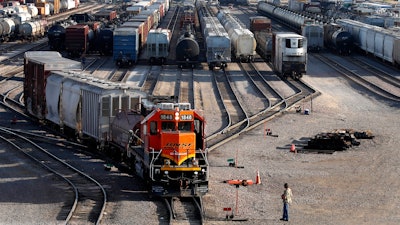 A BNSF rail terminal worker monitors the departure of a freight train, June 15, 2021, Galesburg, Ill.