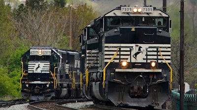 A Norfolk Southern freight train passes a train as it approaches a crossing, Homestead, Pa., April 27, 2022.