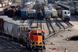 A BNSF rail terminal worker monitors the departure of a freight train, June 15, 2021, Galesburg, Ill.
