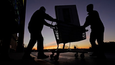 People carry a television to their car at a Best Buy store, Overland Park, Kan., Nov. 26, 2021.
