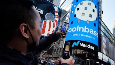 Coinbase employee Daniel Huynh holds a celebratory bottle of champagne as he photographs outside the Nasdaq MarketSite, Times Square, New York, April 14, 2021.