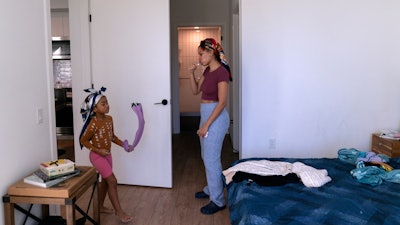 Johnae Strong brushes her teeth as she prepres her 10-year-old son and 6-year-old daughter Jari Akim, left, for school, Feb. 10, 2023, Chicago.